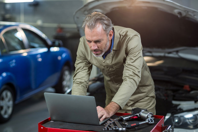 mechanic repairing car with laptop